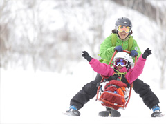 新潟のスキーバケーションの様子。誰でもスキーは、楽しめるというコンセプトのもと、バイ・スキーというチェアスキーで、生まれて初めて、念願のスキーを楽しむ。スキーインストラクターも、病児へのプログラムを一緒に実施することで、彼ら自身の学びになると好評である。