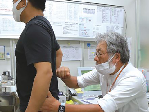 外来診察室でフィリピン人患者さんを打診する様子