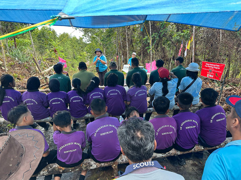 植林活動の大切さなどの説明を熱心に聴いている小学生